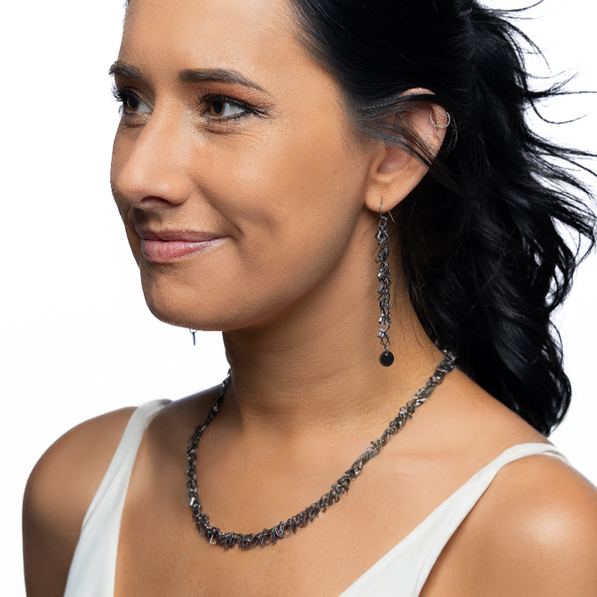 Woman wearing a white top and black jewelry on a white background